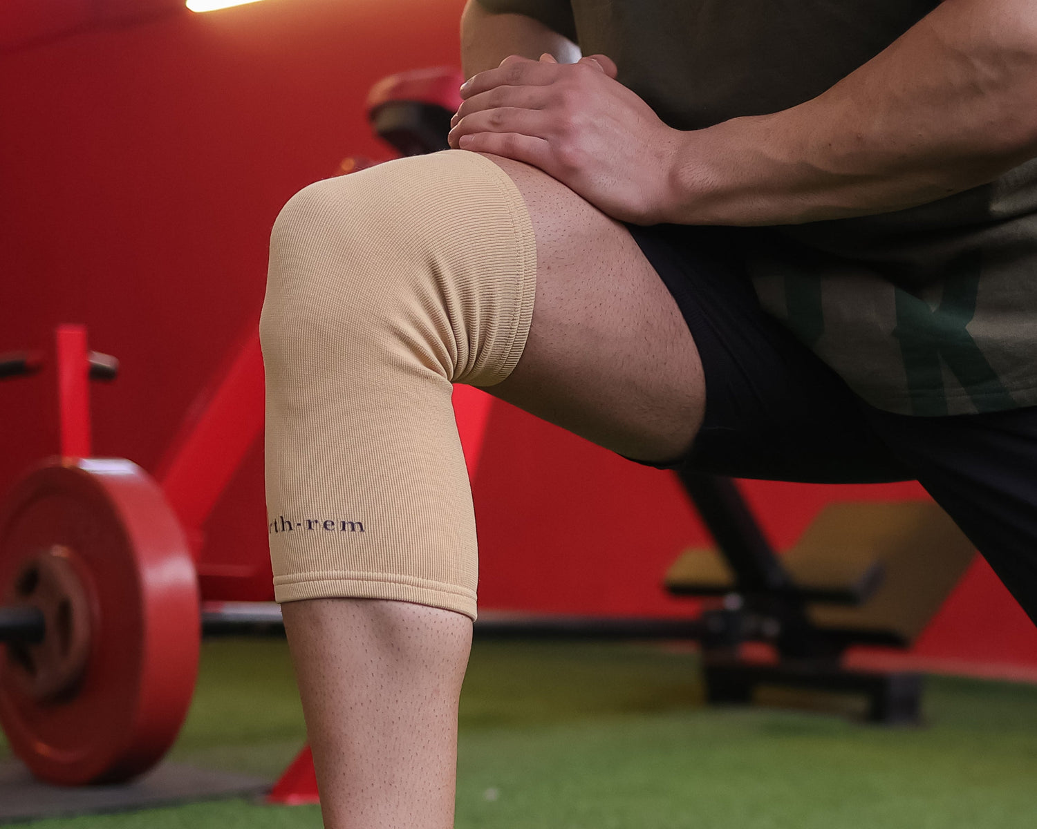 Person wearing a beige knee brace in a gym setting